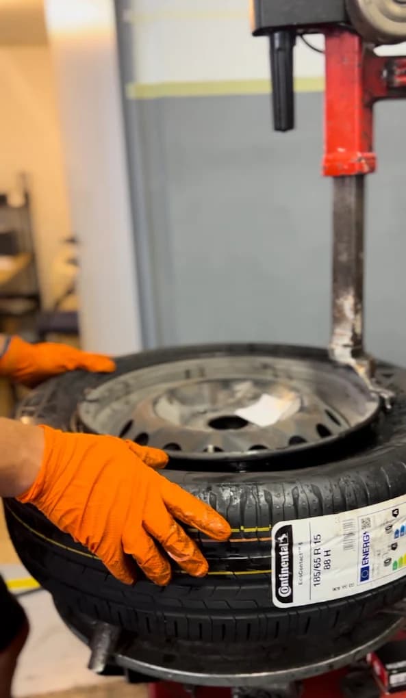 Mecânico de luvas laranja a montar um pneu Continental numa máquina de pneus