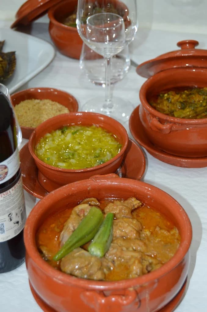 Mesa posta com panelas de barro, farinha de mandioca, molho e vinho