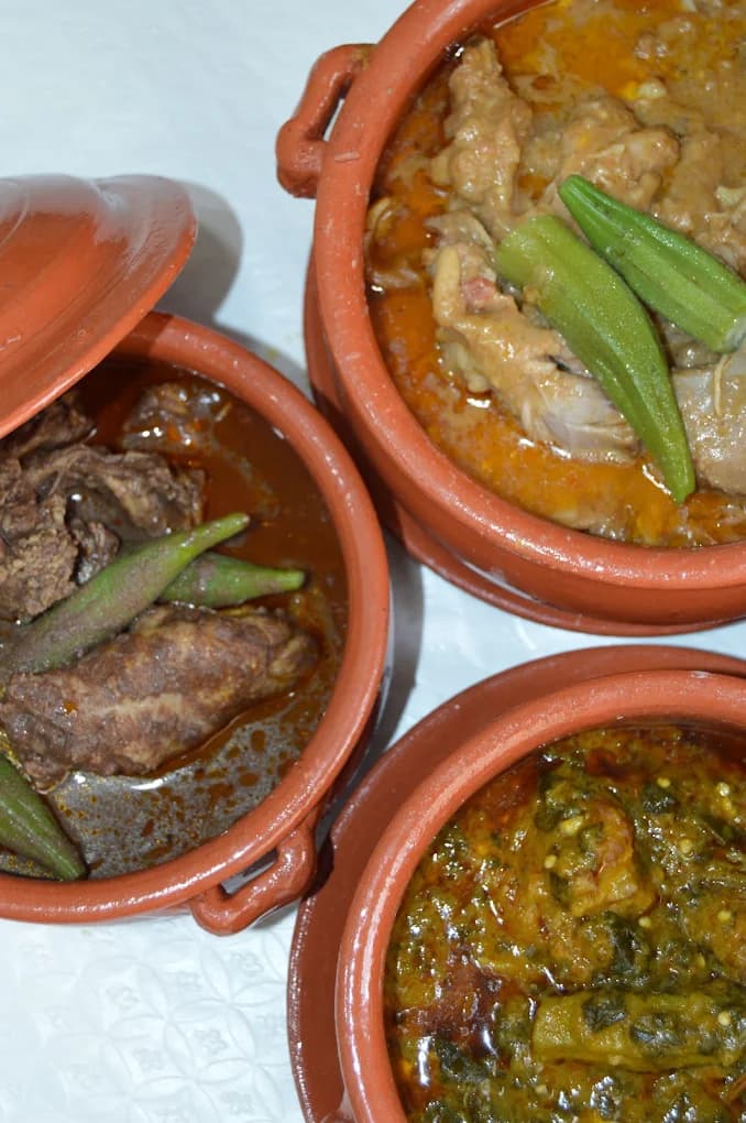 Três panelas de barro com muamba de galinha, carne e kizaca