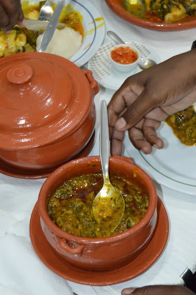 Refeição partilhada à mesa, com as panelas de barro ao centro