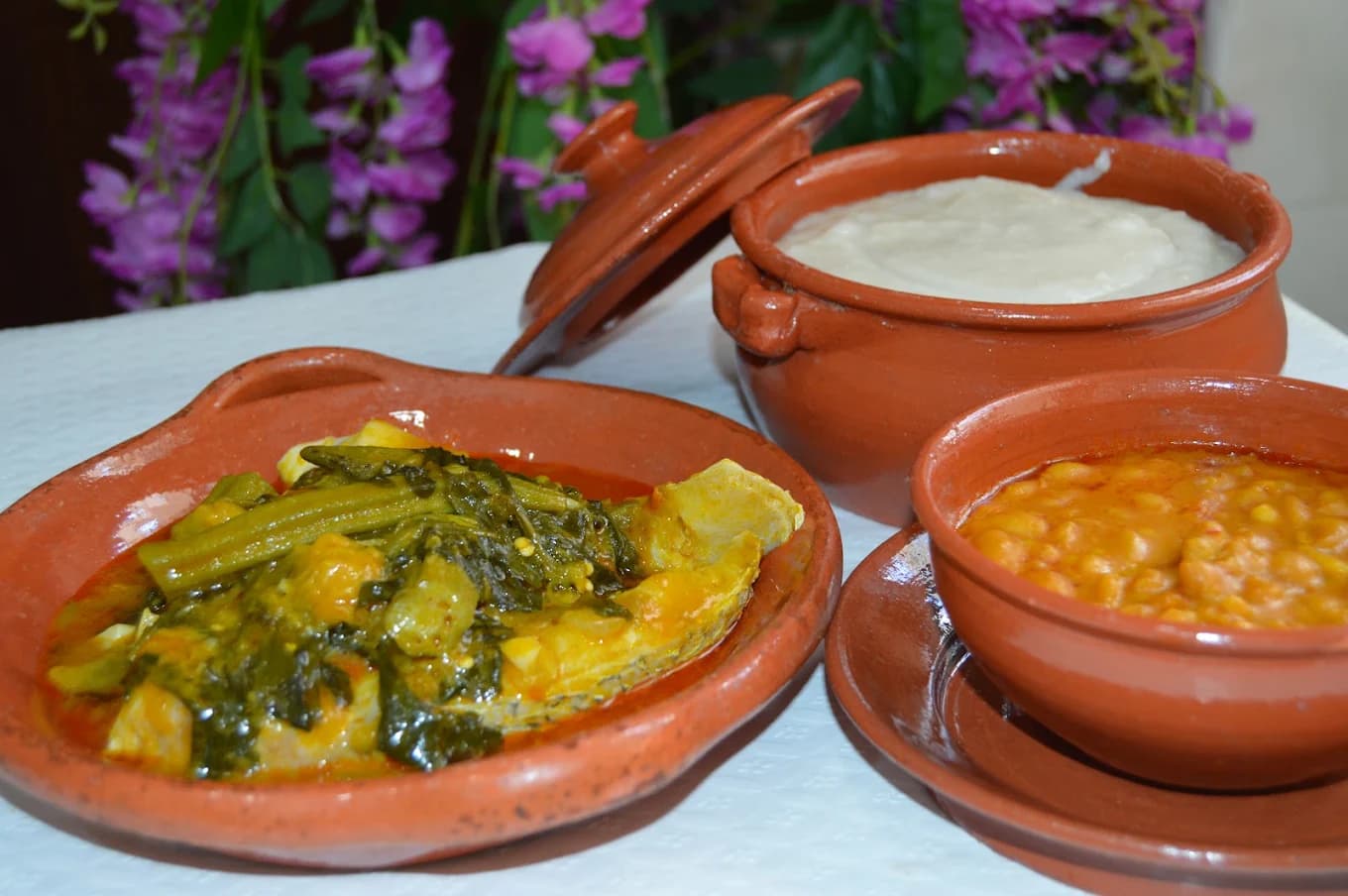 Refeição servida em louça de barro: peixe com kizaca, funge e feijão de óleo de palma