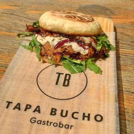 Sandes assinatura do Tapa Bucho servida numa tábua de madeira com o logótipo do gastrobar