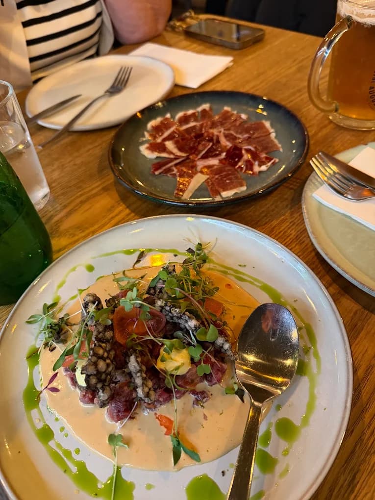 Tártaro de atum com presunto ibérico servido à parte, sobre a mesa de madeira